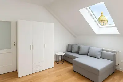 a white living room with a couch and a window at Stylish Studio in the Heart of Prague in Prague