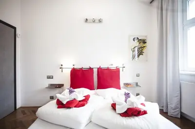 a bedroom with two white beds with red pillows at Central river view in Prague