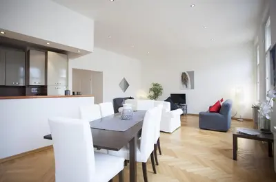 a dining room and living room with a table and white chairs at Charles Bridge Apartment in Prague