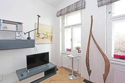 a white living room with a tv and a tree branch at Stylish river-view apartment in Prague