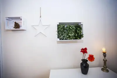a white wall with a vase with a flower on a table at Spectacular Riverview apartment in Prague
