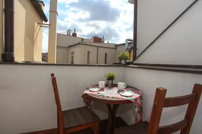 a table and chairs on a balcony with a window at Charles bridge unique maisonette in Prague