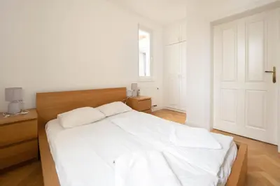 a white bedroom with a white bed and a window at Charles bridge unique maisonette in Prague