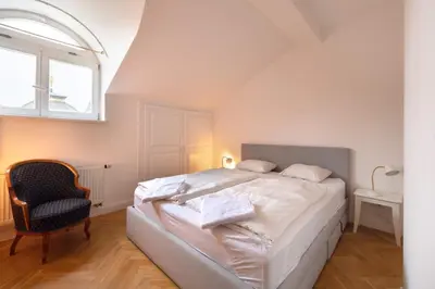 a bedroom with a bed and a chair and a window at Charles bridge unique maisonette in Prague