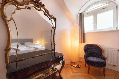 a bedroom with a mirror and a bed with a chair at Charles bridge unique maisonette in Prague