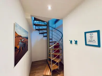 a spiral staircase in a room with a painting at Attic 15 min to Charles Bridge in Prague