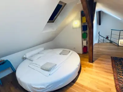 a large white bed in a room with a staircase at Attic 15 min to Charles Bridge in Prague