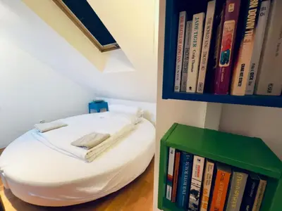 a room with a white bean bag chair next to a book shelf at Attic 15 min to Charles Bridge in Prague