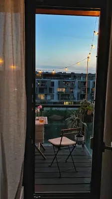 a balcony with a table and a chair on a deck at Riverside serenity Modern apartment with sunset views in Prague