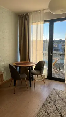 a dining room with a table and chairs and a large window at Riverside serenity Modern apartment with sunset views in Prague