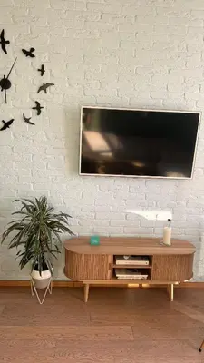a living room with a tv on a white brick wall at Riverside serenity Modern apartment with sunset views in Prague