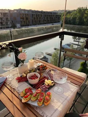 a table with sandwiches and other food on a balcony at Riverside serenity Modern apartment with sunset views in Prague