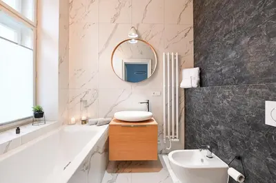 a bathroom with a tub and a sink and a mirror at Elegant Garden Apartment near Main Station in Prague