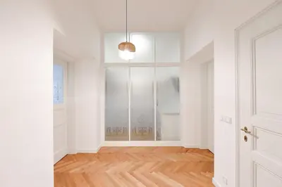 an empty room with a large window and a wooden floor at Elegant Garden Apartment near Main Station in Prague