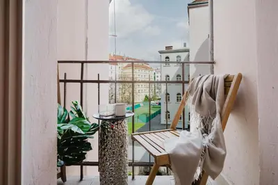 a chair on a balcony with a view of a building at Spacious 2BR Vršovice | AC • Netflix • Cozy Stay in Prague