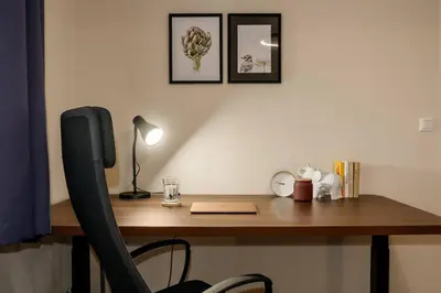 a desk with a laptop and a lamp on it at Spacious 2BR Vršovice | AC • Netflix • Cozy Stay in Prague