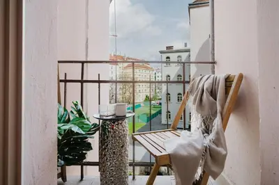 a balcony with a chair and a table and a view at Spacious 2BR Vršovice | AC • Netflix • Cozy Stay in Prague