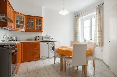 a kitchen with a table and chairs and a kitchen with a stove and a window at Hubert Family Rezidence Prague in Prague