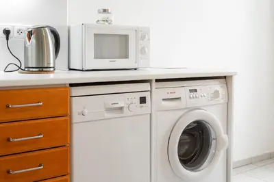 a kitchen with a microwave and a washing machine at Hubert Family Rezidence Prague in Prague