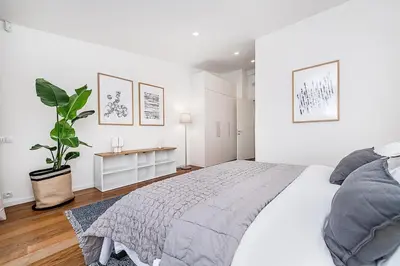 a white bedroom with a bed and a potted plant at Stunning Modern 2bedroom with Iconic View in Prague