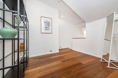 a white room with a staircase and a green vase on the wall at Stunning Modern 2bedroom with Iconic View in Prague