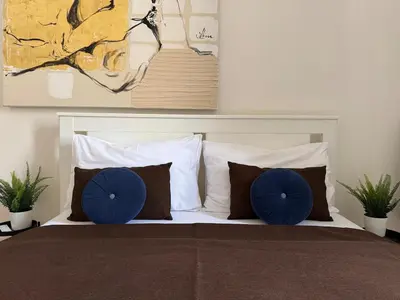 a bedroom with a bed with blue pillows and a painting at Alabaster - Prague Apartment in Prague