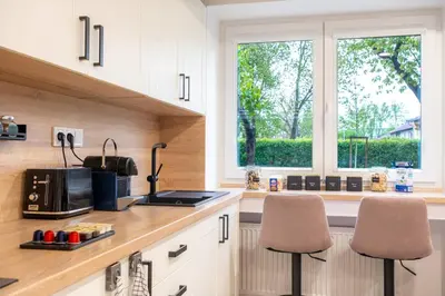 a kitchen with white cabinets and a window and two chairs at Secret Garden Studio in Prague