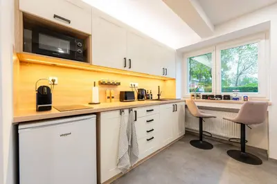 a kitchen with white cabinets and a counter with two chairs at Secret Garden Studio in Prague