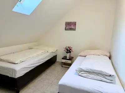 two beds in a small room with flowers on a table at Ubytovna u Maiky in Libochovice