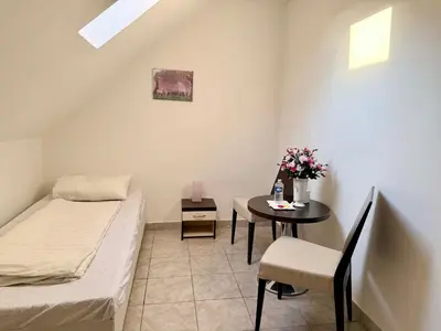 a small room with a bed and a table with flowers at Ubytovna u Maiky in Libochovice