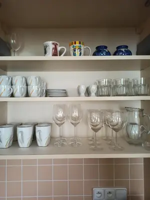 a shelf with wine glasses and plates and bowls at Spacious apartment with garden and private parking in Prague