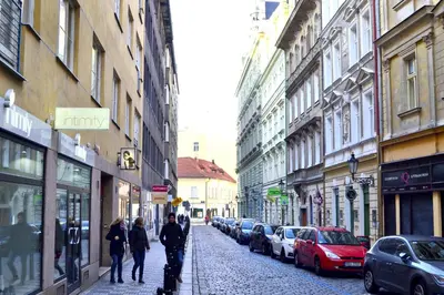 a group of people walking down a street with parked cars at Prague Old Town Apartment Benediktska 6 in Prague