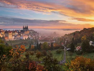 a view of a city at sunset with fog in the valley at Romantic Apartman by Prague Castle in Prague