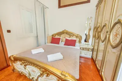 a bedroom with a gold bed with two red pillows at 3BR Apartment in Old Town - Self Check-in - Prague 1 - Sleep up to 8 in Prague