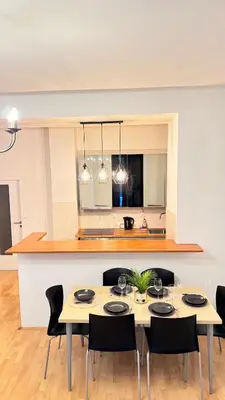 a dining room with a table with chairs and a kitchen at Florenc Grant Apartments in Prague