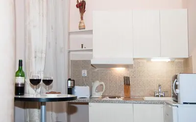 a kitchen with white cabinets and two glasses of wine at Just For Two Ruterra Studio in Prague