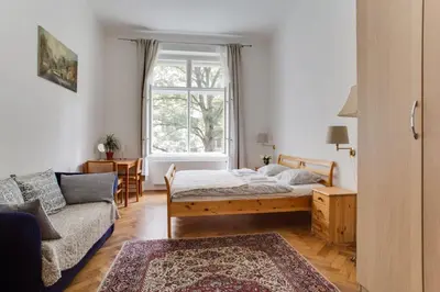 a bedroom with a bed and a couch and a window at Charming 2BR Garden Views in Historic Vinohrady in Prague