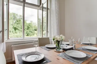 a dining room with a wooden table and a window at Charming 2BR Garden Views in Historic Vinohrady in Prague