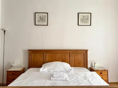 a bed with white sheets and two pictures on the wall at Spacious 2BR in Historical Vinohrady in Prague