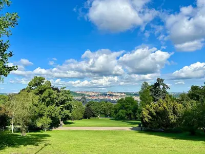 a green park with trees and a blue sky with clouds at Spacious 2BR in Historical Vinohrady in Prague