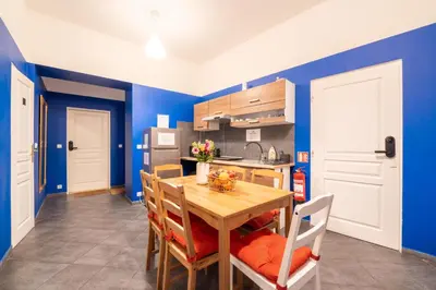 a kitchen with blue walls and a wooden table and chairs at Luna Female Hostel in Prague