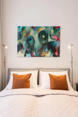 a bed with two pillows and a painting above it at High-End Apartments with AC Steps from Wenceslas Square by EasyBNB Premium in Prague