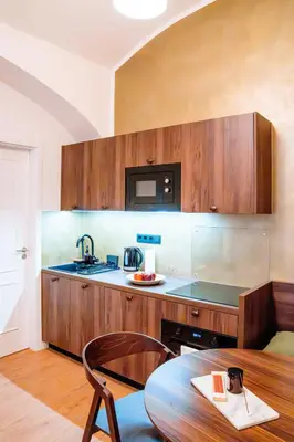 a kitchen with wooden cabinets and a table and a microwave at Amber Nest in the Heart of Prague in Prague
