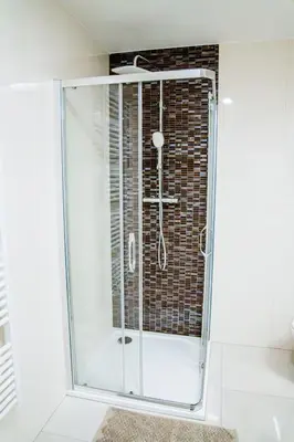 a glass shower in a bathroom with a brick wall at Amber Nest in the Heart of Prague in Prague