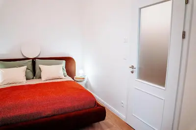a bedroom with a red bed and a white door at Amber Nest in the Heart of Prague in Prague