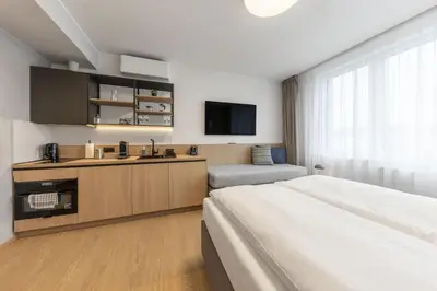 a hotel room with a large bed and a kitchen at Malleta Living in Prague