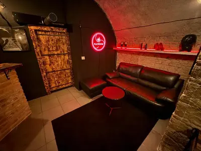 a living room with a leather couch and a neon sign at Playroom Prague Karlín in Prague