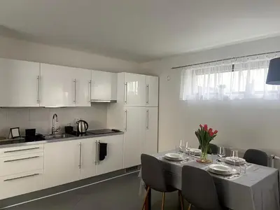 a kitchen with white cabinets and a table with chairs at Garden studio in the heart of Vinohrady in Prague