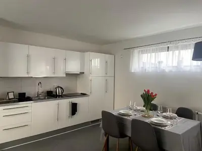 a kitchen with white cabinets and a table with chairs at Garden studio in the heart of Vinohrady in Prague
