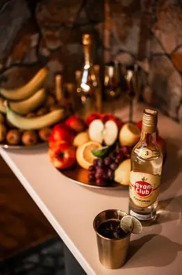 a table with a plate of fruit and a bottle of alcohol at Coco Suite Private Spa and Jacuzzi Prague Center in Prague